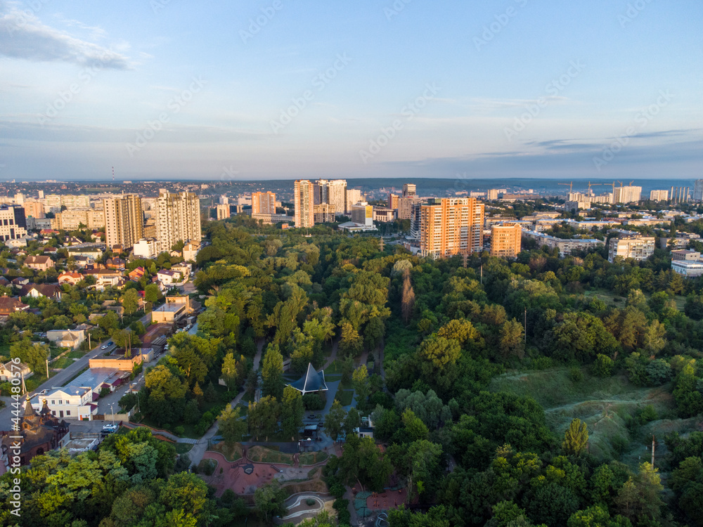 Aerial morning view on green summer Kharkiv city center popular recreation park Sarzhyn Yar. Botanical garden with water spring and playground in residential area in sunrise light