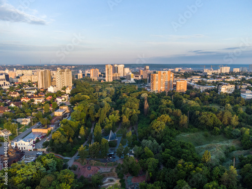Aerial morning view on green summer Kharkiv city center popular recreation park Sarzhyn Yar. Botanical garden with water spring and playground in residential area in sunrise light