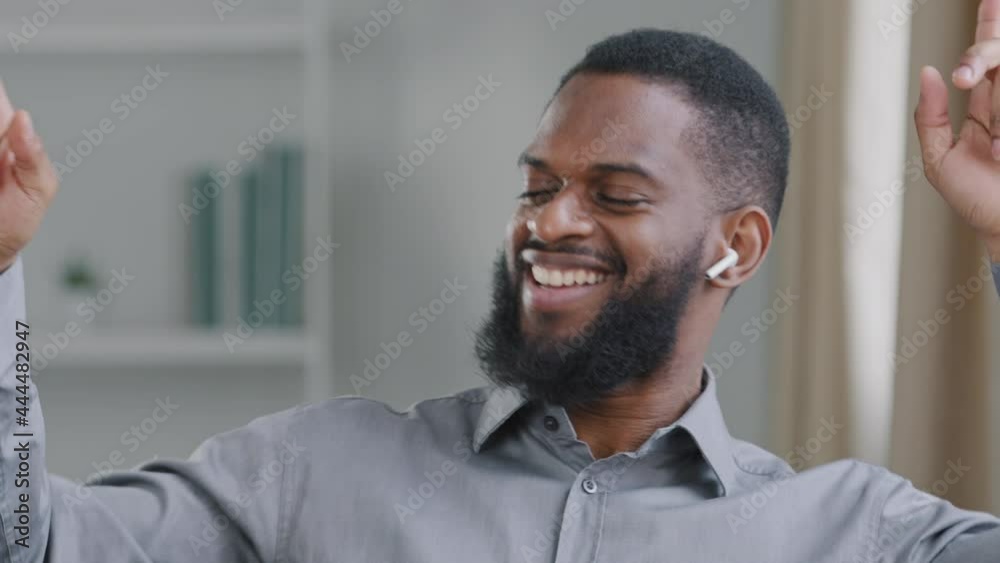 Black millennial mixed race young man corporation manager wearing wireless headphones listening music relaxing during office break. African American student enjoying favorite composition listens hit Black millennial mixed race young man corporation manager wearing wireless headphones listening music relaxing during office break. African American student enjoying favorite composition listens hit