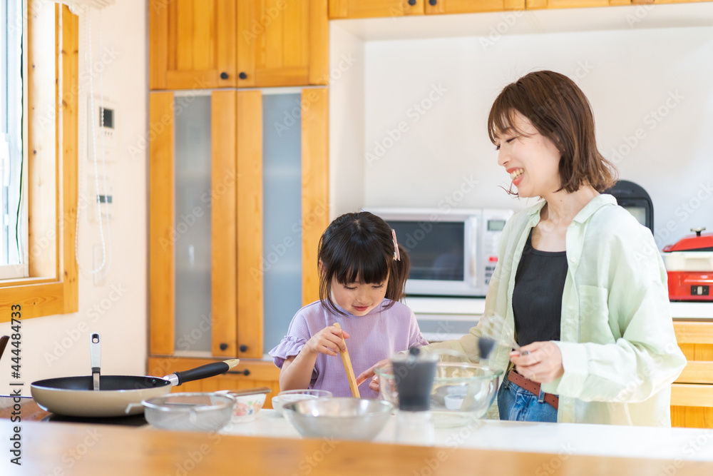 お母さんと一緒に料理をする小さな女の子