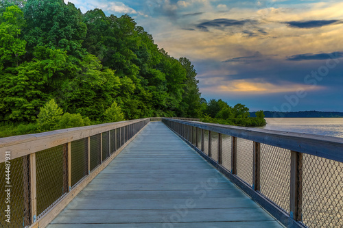 Pedestrian bridge and lake color reflections with a cloudy sunset