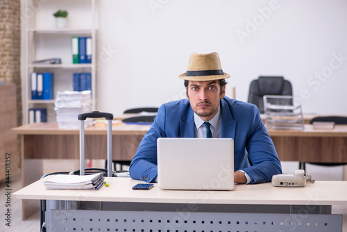 Young male employee preparing for trip in the office