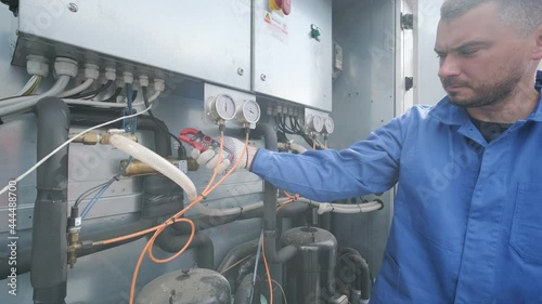 The technician checking power lines of the heat exchanger with current clamps photo