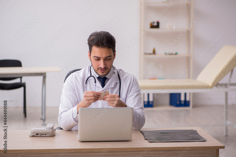 Young male doctor holding pills in the clinic Young male doctor holding pills in the clinic