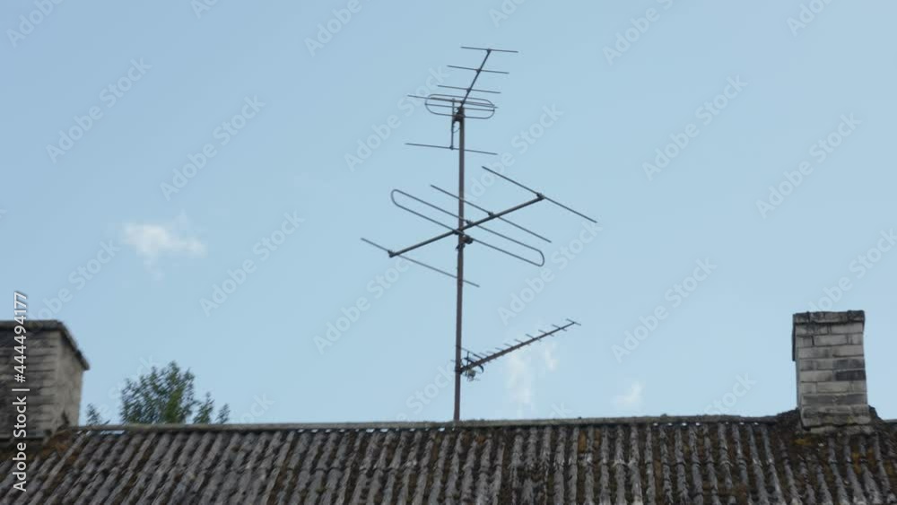 The satellite antenna on top of the roof of the old wooden house in Estonia The satellite antenna on top of the roof of the old wooden house in Estonia