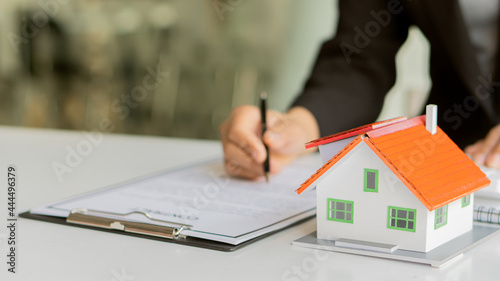 Real estate agents are working on paperwork and house plans on the table to offer purchase and lease agreements with financing.