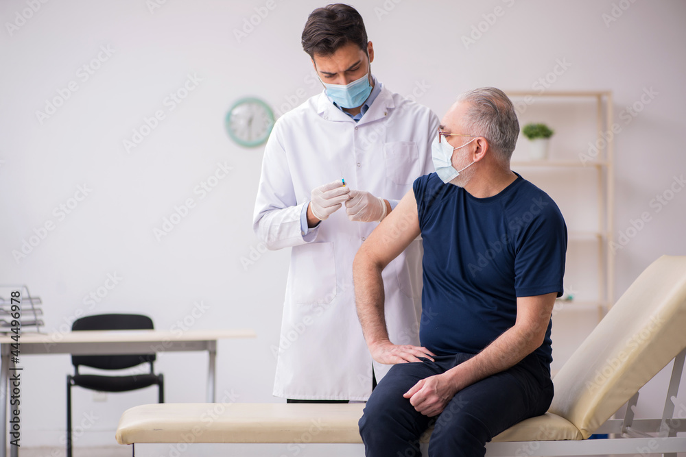 Old male patient visiting young male doctor in vaccination conce Old male patient visiting young male doctor in vaccination conce