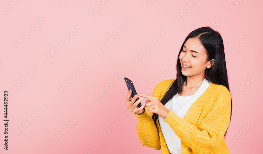Happy Asian portrait beautiful cute young woman teen smiling excited typing text message on smart mobile phone enjoys online communication isolated, studio shot on pink background with copy space Happy Asian portrait beautiful cute young woman teen smiling excited typing text message on smart mobile phone enjoys online communication isolated, studio shot on pink background with copy space