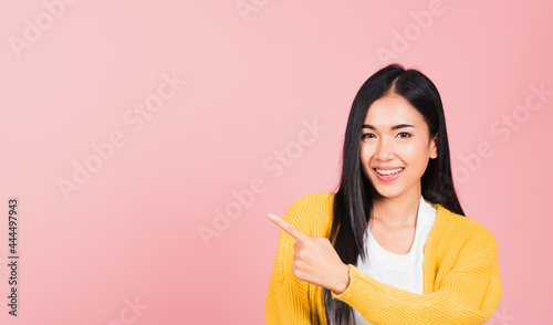 Asian happy portrait beautiful cute young woman standing makes gesture one fingers point upwards above presenting product something  studio shot isolated on pink background with copy space