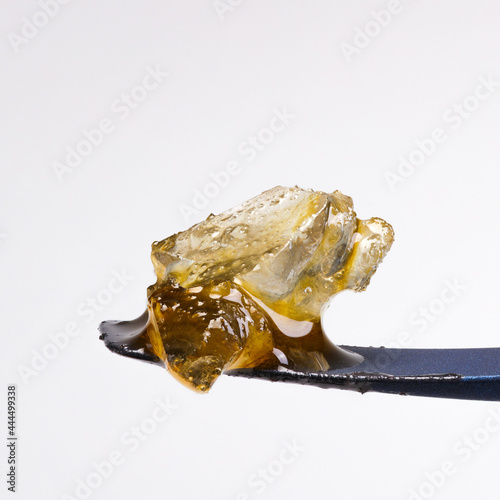 Close up of some live resin diamonds with a white background sitting on a titanium dab tool. 