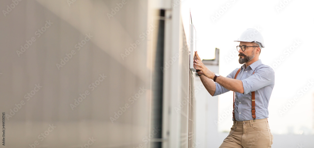 Portrait of Technician Electrical Engineer at rooftop building. Clean and green alternative energy concept.