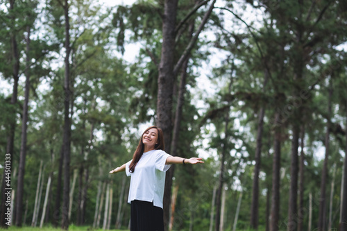 Portrait image of a happy young asian woman with arms opening in the park