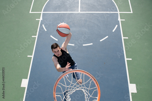 Angle view of man playing basketball, above hoop of man shooting basketball. © Volodymyr