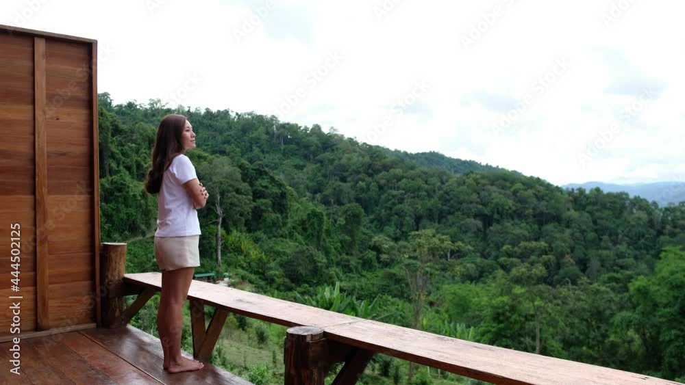 A woman standing on balcony and looking at a beautiful greenery mountains and nature view A woman standing on balcony and looking at a beautiful greenery mountains and nature view