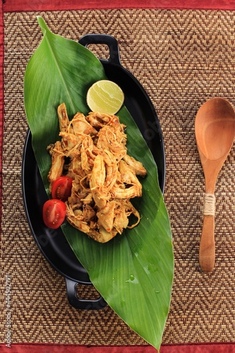 Top View Ayam Suwir Bumbu Kuning (Ayam Sisit with Yellow Spice) is a Balinese or Indonesian Cuisine Made From from Chunks of Chicken Meat. Served on Black Oval Plate, Copy Space for Text or Recipe photo