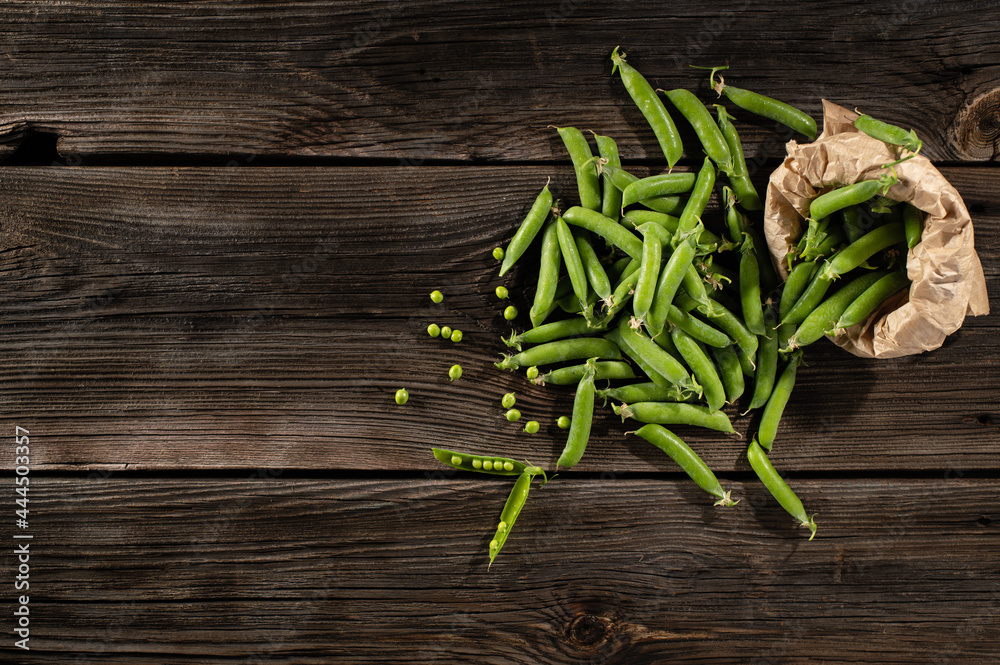 green young peas in pods, freshly picked on old brown boards, top view, empty space for text green young peas in pods, freshly picked on old brown boards, top view, empty space for text