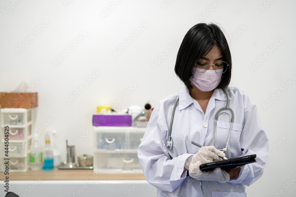 Asian Female Doctor With Stethoscope On Her Neck And write record on tablet In Her Hands,Doctor Stand in office Asian Female Doctor With Stethoscope On Her Neck And write record on tablet In Her Hands,Doctor Stand in office