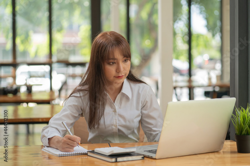 Free Download Portrait of a pretty young woman using her laptop in the office. - GFXLoad