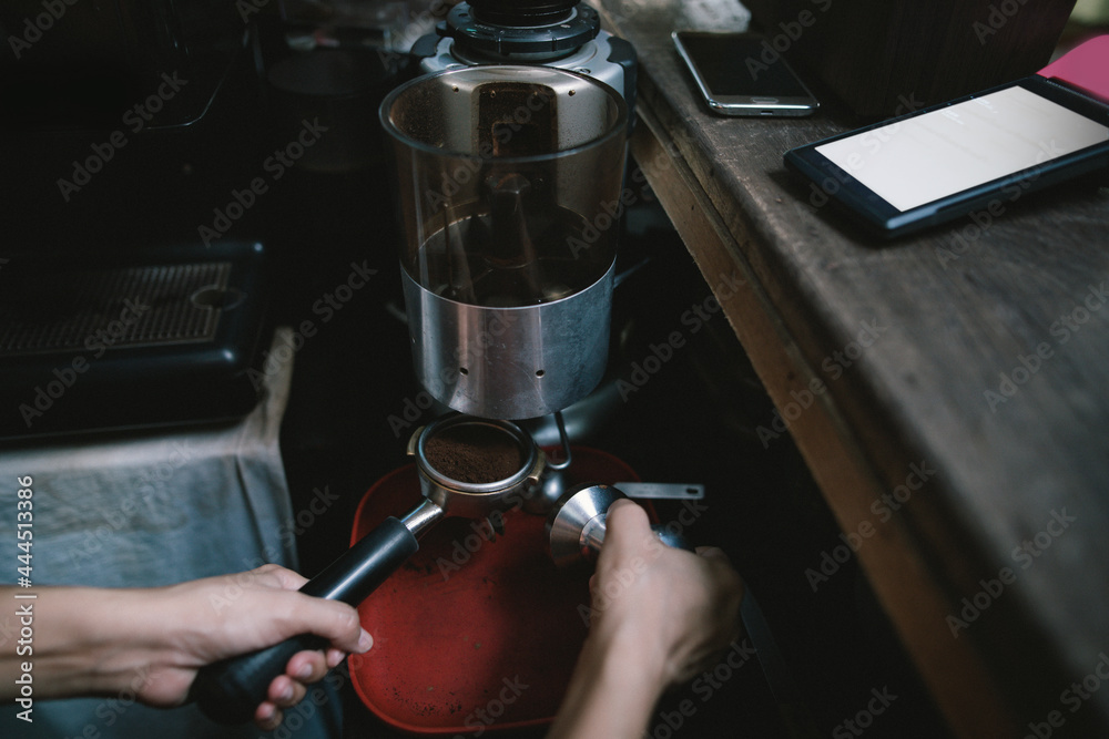 The barista is taking the finished coffee out of the grinder. before bringing to make coffee for customers According to the drink order, request the delivery system.