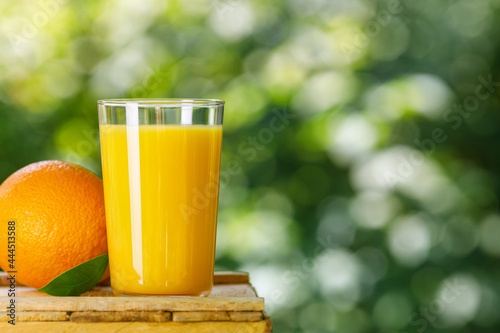 glass of orange juice with ripe fruit outdoors