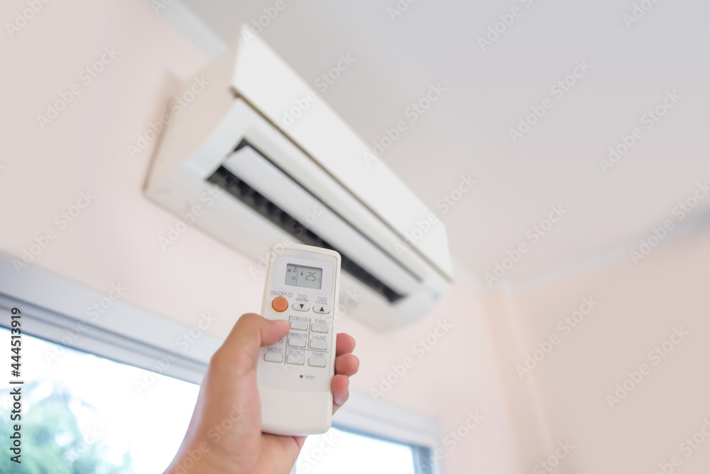 Close up remote set adjust temperature at 25 degrees of air conditioner split type wall mounted in home room concepts of cool or heat air cleaner and service repairing and maintenance. Close up remote set adjust temperature at 25 degrees of air conditioner split type wall mounted in home room concepts of cool or heat air cleaner and service repairing and maintenance.