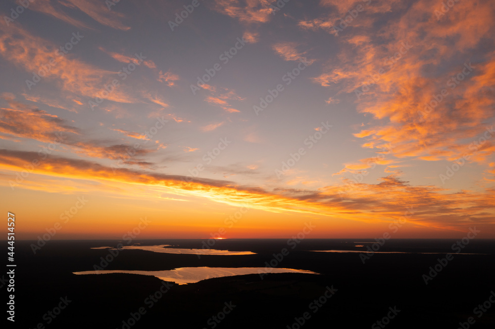 Aerial view of a sunset sky background. Aerial Dramatic gold sunset sky with evening sky clouds over the lake. Stunning sky clouds in the sunset. Sky landscape. Aerial photography.