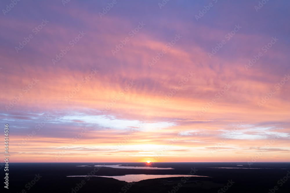 Fototapeta premium Aerial view of a sunset sky background. Aerial Dramatic gold sunset sky with evening sky clouds over the lake. Stunning sky clouds in the sunset. Sky landscape. Aerial photography.
