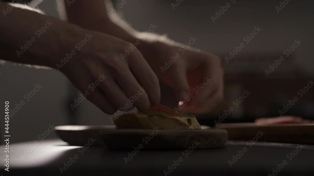 Slow motion man put salami on baguette slices on olive wood board Slow motion man put salami on baguette slices on olive wood board