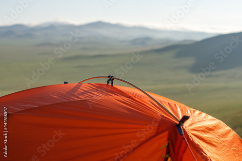 part of the orange tent against the background of a blurred hilly valley