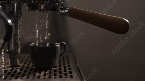 dark early morning shot of rinsing coffee machine before making esprresso