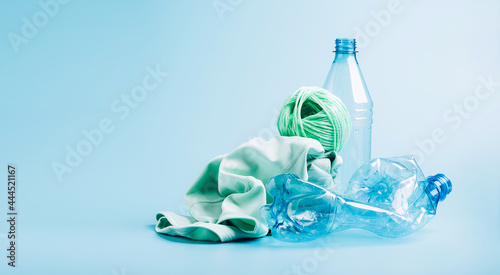 Empty plastic bottle and various fabrics made of recycled polyester fiber synthetic fabric on a blue background photo