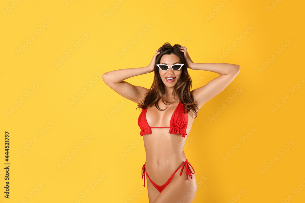 Beautiful woman in stylish bikini and sunglasses on yellow background Beautiful woman in stylish bikini and sunglasses on yellow background