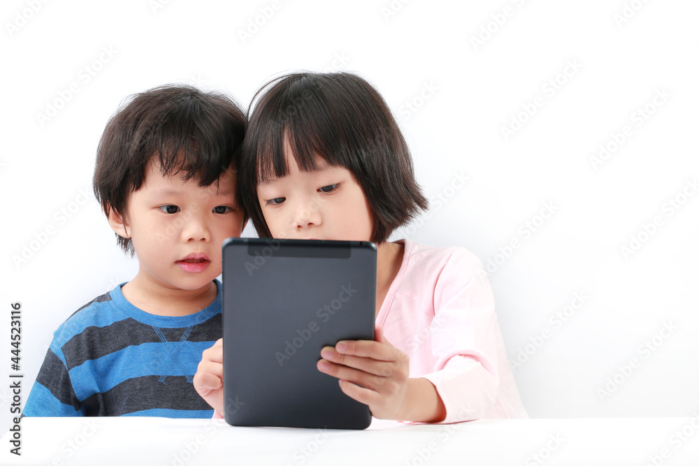 Cute little Asian boy and girl sharing using a tablet computer against white background Cute little Asian boy and girl sharing using a tablet computer against white background