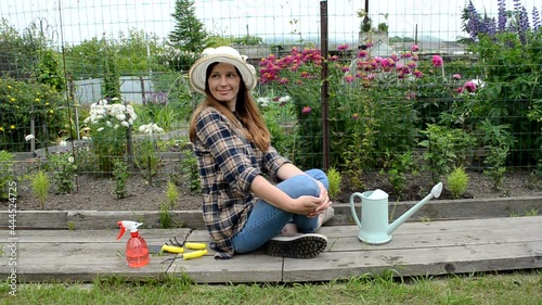 caucasian woman in garden with flowrs relaxing after working photo