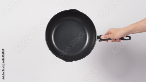 Pan cleaning. Man hand on white background cleaning the non stick pan with handy dish washing sponge which yellow color on the soft side and green on hard side for hygiene after cook. Electric pan. 
 photo