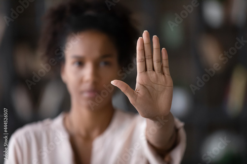Close up of African American woman showing stop gesture with hand blurred background, young female protesting against domestic violence and abuse, bullying, saying no to gender discrimination photo