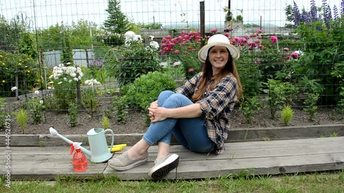 caucasian woman in garden with flowrs relaxing after working photo