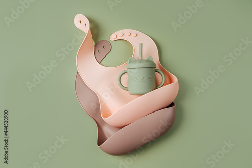 Silicone baby bibs on green background. First baby accessories for dinner. Top view, flat la photo