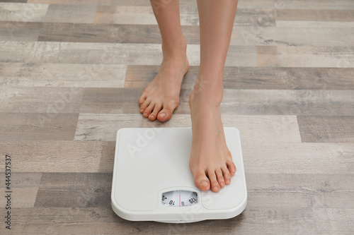 Woman stepping on floor scales, closeup. Weight control photo