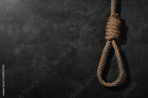 Tied rope noose against grey stone background. Space for text