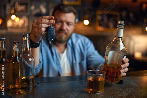 Drunk man with car key sitting at counter in bar