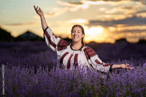 Young woman in Romanian folklore costume harvesting lavendere photo