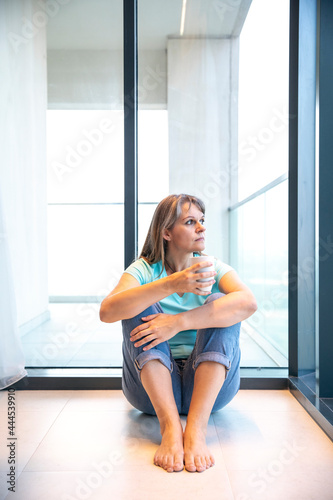 middle aged woman looking out of her window