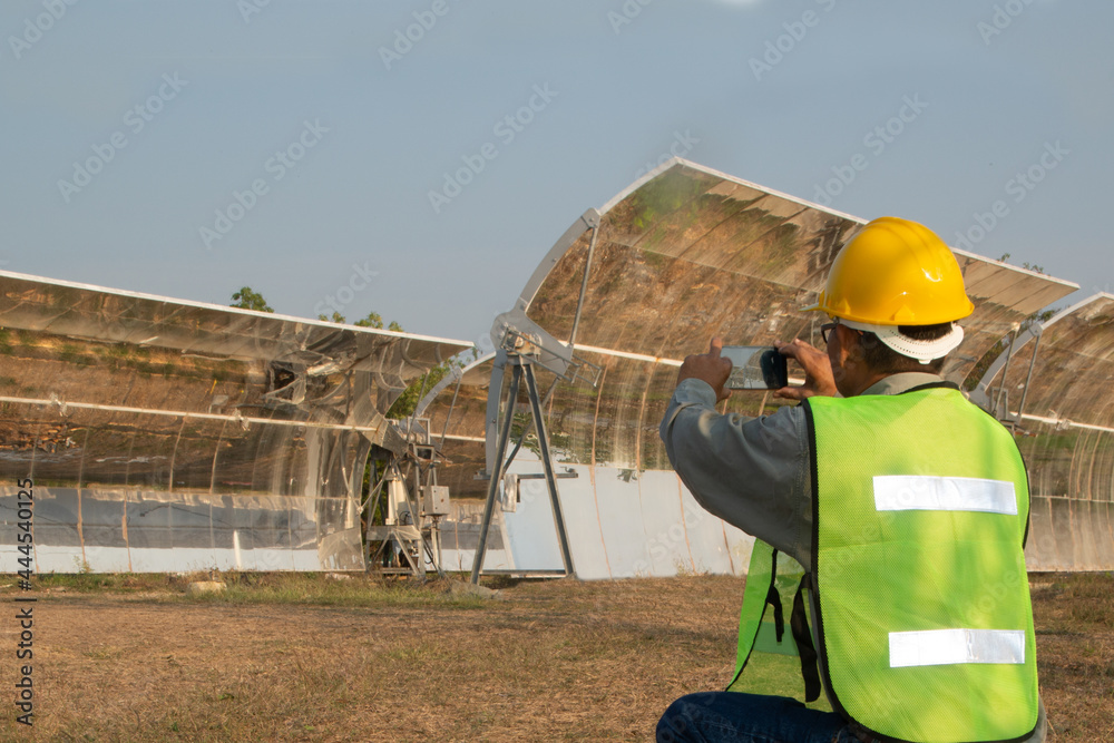 Uniformed and helmeted officers inspect and photograph parabolic solar rails using their mobile phones. Uniformed and helmeted officers inspect and photograph parabolic solar rails using their mobile phones.