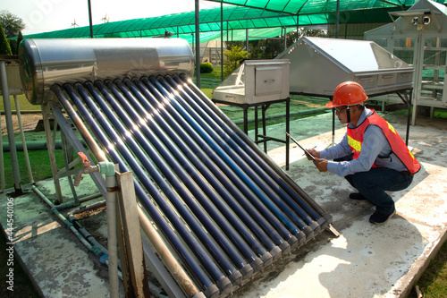 The Asian worker in uniform and helmet checks concentrating Solar Power with Flat Plat collector and Evacuum Tube Collector.
