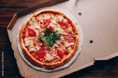 Tasty pizza in delivery box on dark wooden background
