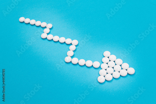 Global Pharmaceutical Industry and Medicinal Products - Downward Arrow Made from White Pills on Blue Background