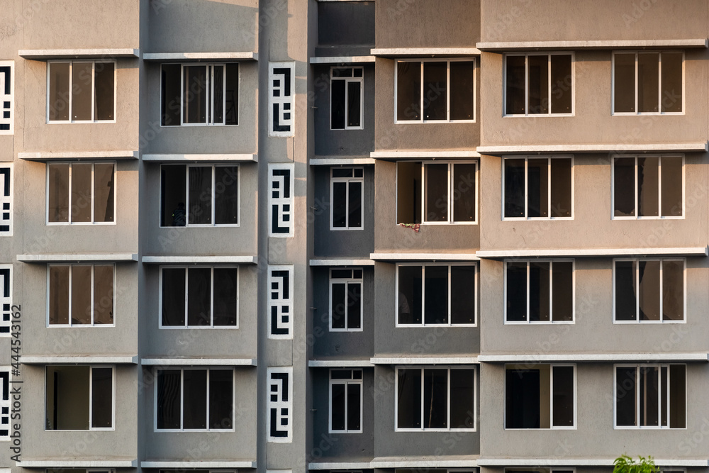 Windows on the exterior facade of a grey modern concrete high rise apartment building in suburban Mumbai.