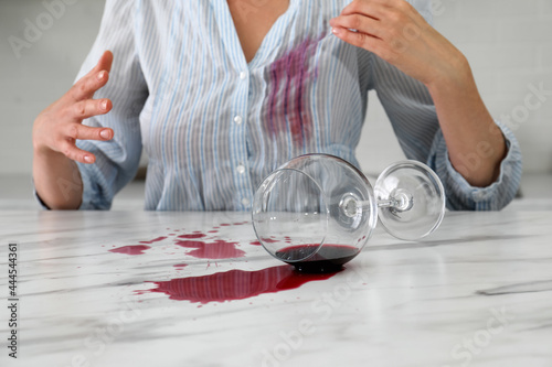 Foto Woman with spilled glass of wine and stain on her shirt at table indoors, closeu
