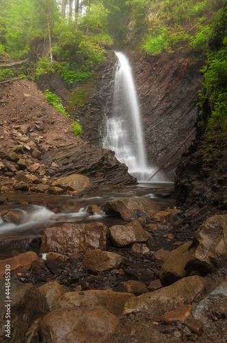 Waterfall in the summer forest. Colorful natural landscape with waterfall with blurry water in the mountains